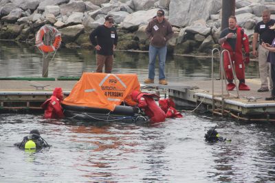 Fishermen climb into a life raft in their immersion suits during safety & survival training. Photo: Judy Benson / Connecticut Sea Grant