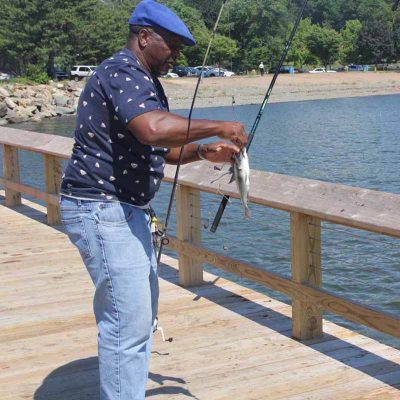 Andre Craig of New Haven unhooks a porgy he caught off the pier at Fort Hale Park at the mouth of the Quinnipiac River on the city's east side.