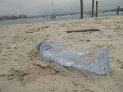 An empty water bottle lies on a Long Island Sound beach