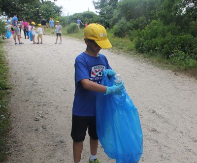 Alex Mynuk deposits an empty water bottle he found off the main trail at Bluff Point into a trash bag.