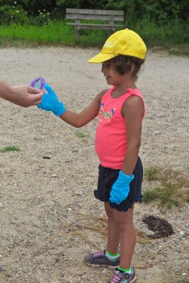 Mystic Aquarium summer camper Athena Costick, 5, receives one of the stickers being given out as part of the #DontTrashLISound campaign.
