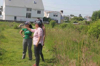 Juliana Barrett talks with student volunteers helping with a restoration project at Dodge Paddock, a coastal preserve in Stonington, last summer.