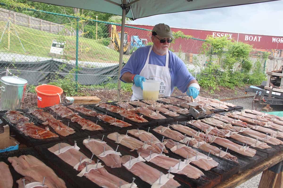 An Essex Rotary Club volunteer adds a special seasoning sauce to shad fillets about to be grilled at the annual Shad Bake at the Connecticut River Museum in June.