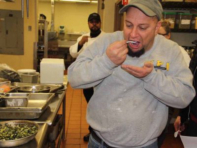 Chris Szewczyk, owner of Taino Smokehouse in Middletown, samples some of the kelp and leek topping for the salmon dish prepared by chef Jeff Trombetta.