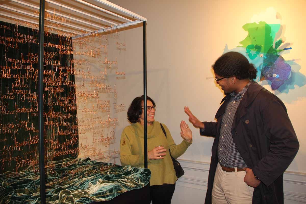 Artist Diane Barceló, left, and Cliff Sebastian of Mashantucket share a high-five during the opening of the "Crosscurrents" exhibit. Barcelo and Ashby Carlisle are the creators of "They Came By Water" work in the foreground, and Sebastian recited Native American words for an audio that accompanied the piece. Behind them is "Sea Form," a work by artist Debbie Hesse.