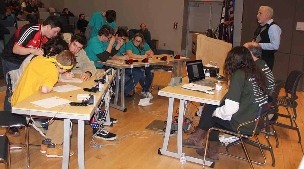 The team from the Science and Technology Magnet High School of Southeastern Connecticut, left, competed against the team from Cogichaug Regional High School in the final round of the 22nd Annual Quahog Bowl. Standing is Evan Ward, science judge for the competition and head of the UConn Marine Sciences Department.