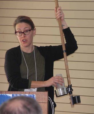 Emily Van Gulick, fish biologist at the state Bureau of Aquaculture, demonstrates proper water sampling techniques to the commissioners.
