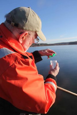 Don Murphy, chairman of the Stonington Shellfish Commission, places a cap onto a newly collected water sample from a shellfishing area in the Mystic River.