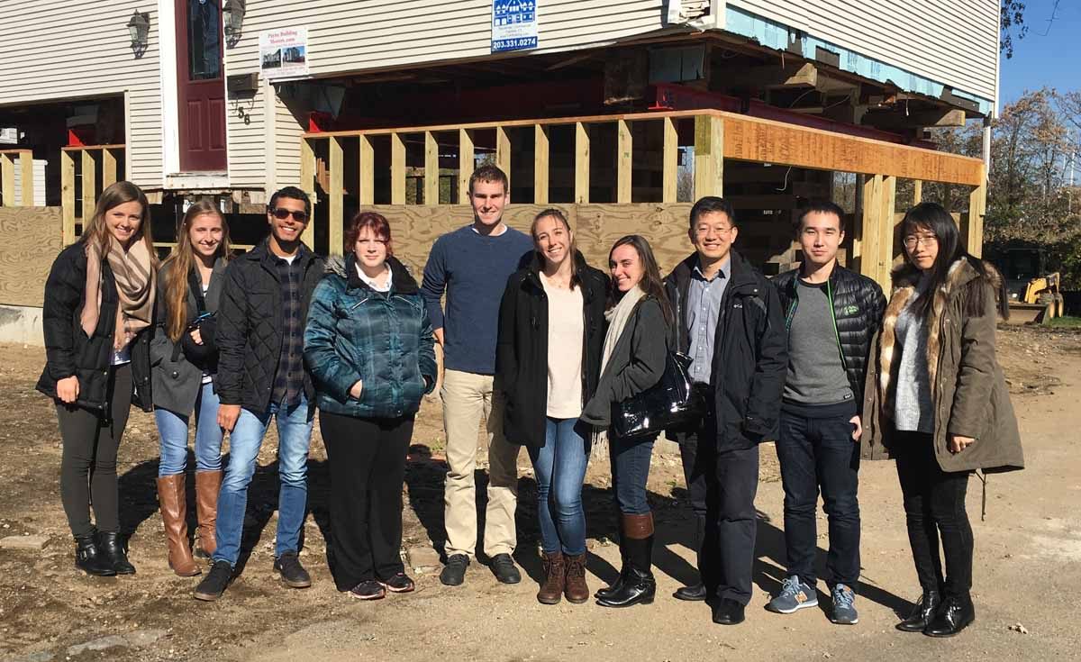 Prof. Wei Zhang, third from right, used this home being elevated in Fairfield as part of his research project. With him are several UConn graduate students, including three who worked on the project.