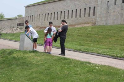 Participants look for clues on one of the interpretive signs at Fort Trumbull.