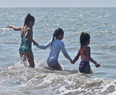 Three girls from the New Britain YWCA summer camp enjoy the waves at Lighthouse Point Park.