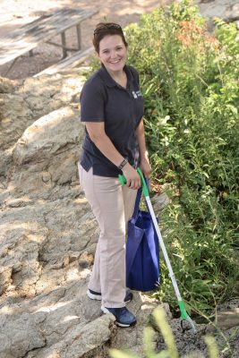 MaryEllen Mateleska, director of education and conservation at Mystic Aquarium, uses a trash picker and a reusable bag to gather trash at Lighthouse Point Park.