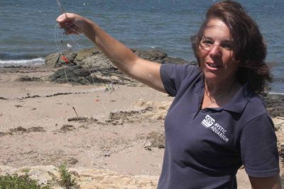 Dale Wolbrink, senior director of public relations at Mystic Aquarium, holds up a tangle of monofilament fishing line she found during the cleanup.