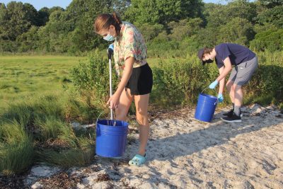 Anna O'Connor, left, a junior at Lyman Memorial High School in Lebanon, and Matthew Fago, a sophomore at RHAM High School in Hebron, search the marsh for trash.