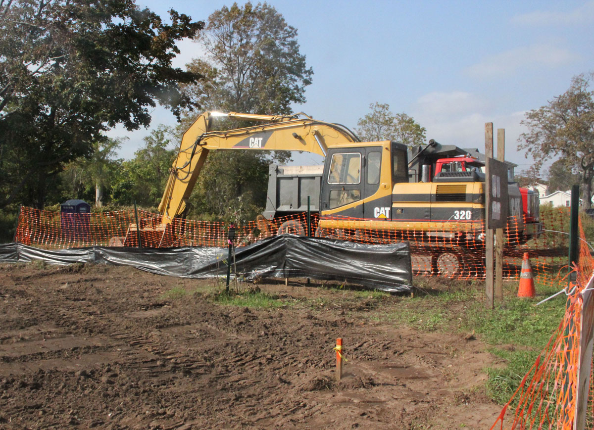 A bulldozer and dump truck are parked beside a former home site being converted into flood plain habitat.
