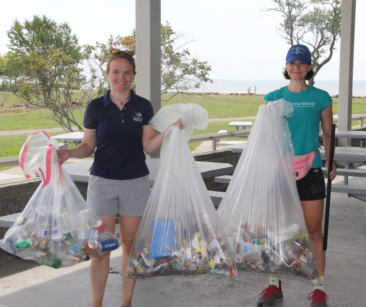 Bridget Cevero of the Maritime Aquarium, left, and Annalisa Paltauf of Save the Sound, hold up the 35.75 pounds of trash collected by volunteers at the cleanup at Sherwood Island State Park.