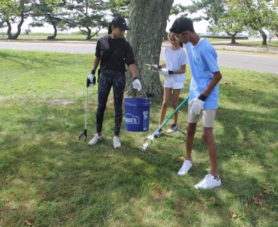 : Palek Mehta, left, and her son Dev and daughter Arya of Westport pick up trash from one of the grassy areas of the park. Dev Mehta is a volunteer at the Maritime Aquarium.