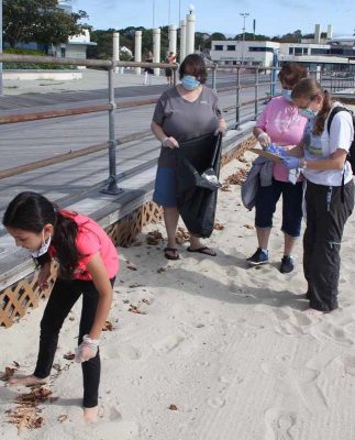 Rebecca Tsai of Groton, left, searches for trash along the edge of the boardwalk as Jeri Buckholt of New London tallies her finds.