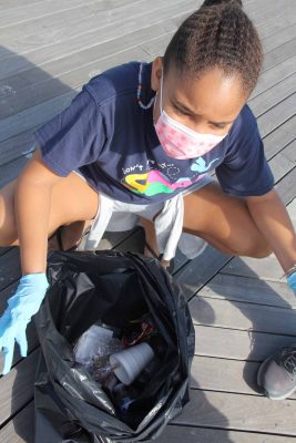 Sveva Brown, a member of New London Girl Scouts, shows some of the trash she collected, including a styrofoam cup, plastic bottles and food wrappers.