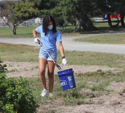 A young woman picks up trash at a public park on Long Island Sound.