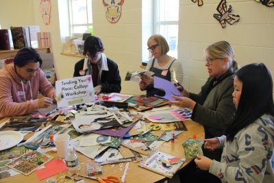 One of two collage-making workshop groups work on their projects.