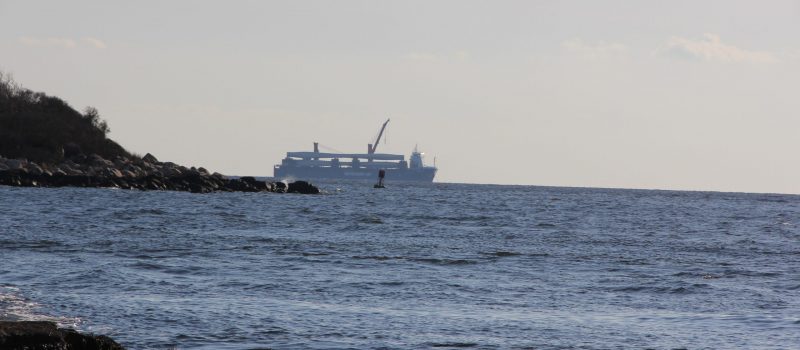 A vessel carrying components for the South Fork offshore wind project passes behind Pine Island offshore from the Avery Point campus on Dec. 13.