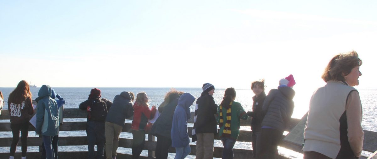 A group of middle school students and their teacher on an observation deck overlooking Long Island Sound.