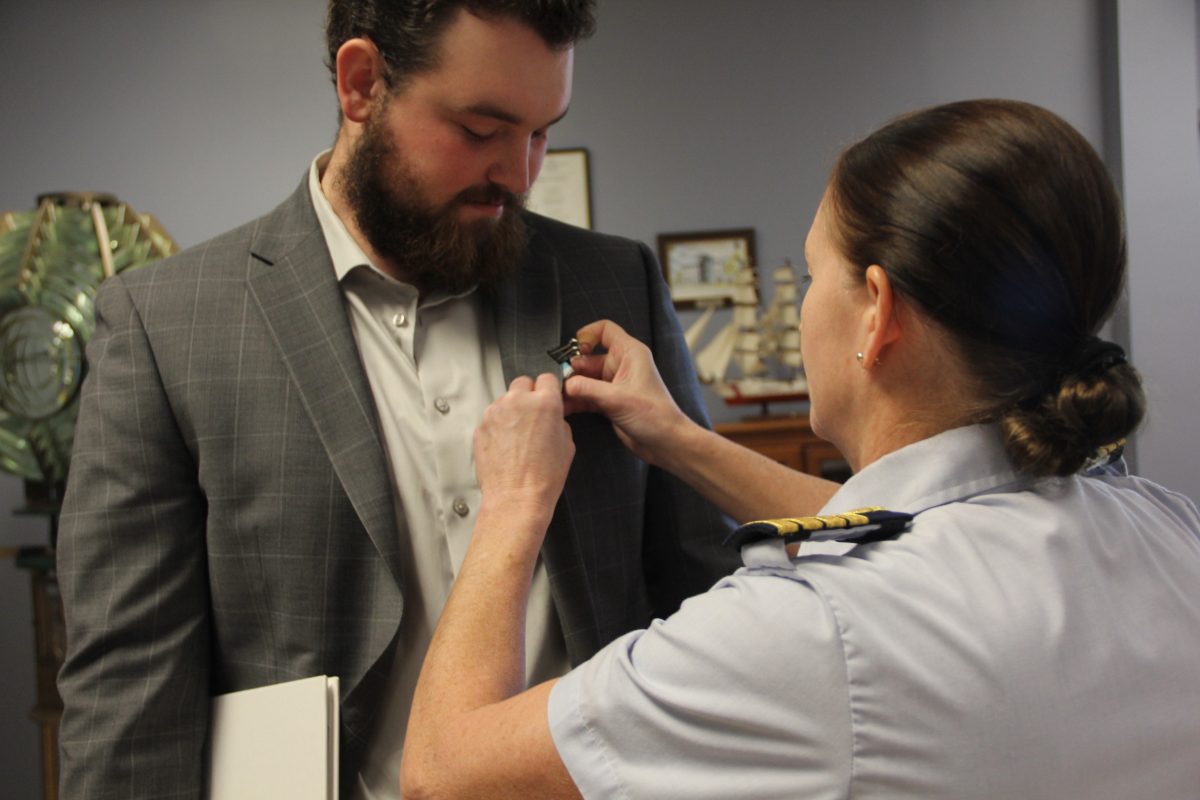 Coast Guard Sector Long Island Sound Commander Captain Elisa M. Garrity pins a medal to John Genther's lapel in honor of heroic act on Nov. 6.