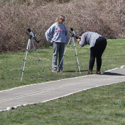 A CT DEEP staff member, left, instructs a visitor on how to use one of the sun spotting telescopes set up at Camp Harkness for the eclipse event.