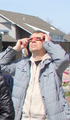 One of the approximately 500 visitors to Camp Harkness views the eclipse through protective eyeglasses.