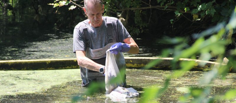 Yale Professor Gaboury Benoit removes trash collected at a boom he placed on the Mill River in New Haven as part of CTSG-funded research into the plastic litter cycle.