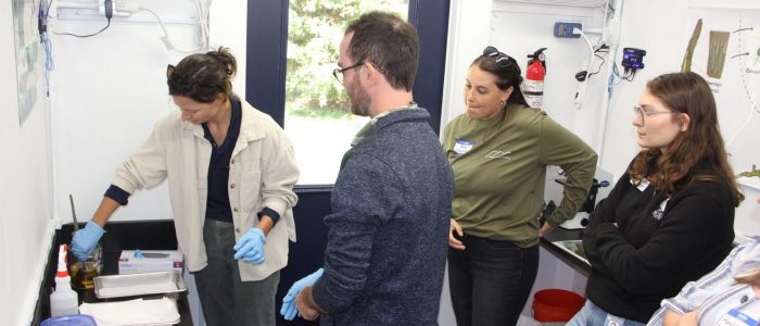 Hannah King of New England Science and Sailing, left, follows instructions from Zach Gordon, CTSG assistant extension educator, center, for preparing kelp sorus tissue to release spores as part of a demonstration for teachers in the CTSG mobile seaweed lab.