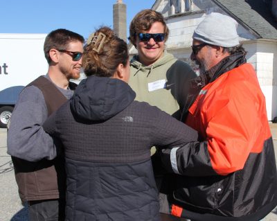 Russell Kingman of Fishing Partnership, right, demonstrates the huddle position used for survivors to make a plan to get to the life raft after abandoning ship in immersion suits.