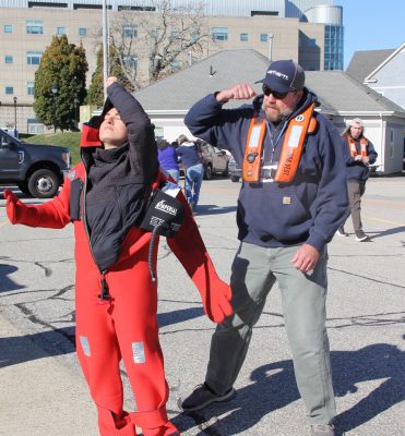 John Quill of Fishing Partnership, right, instructs Alexandra Frenzel, a UConn marine sciences graduate student, how to put on an immersion suit as other students watch.