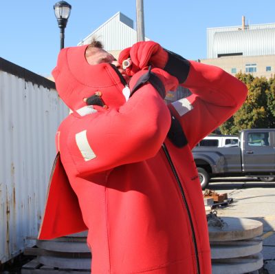 A student in the sea safety workshop zips an immersion suit over his mouth and chin.