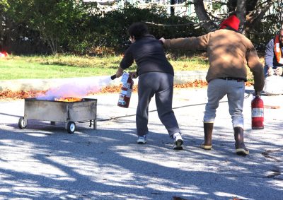 Student practice putting out a fire using fire extinguishers.