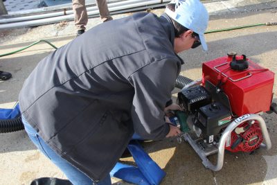 A student practices attaching a clamp onto a pump to repair a leak.