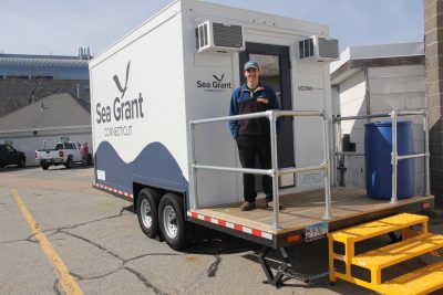 Clayton McGoldrick, lab technician for Connecticut Sea Grant, stands on the deck of the mobile seaweed lab.