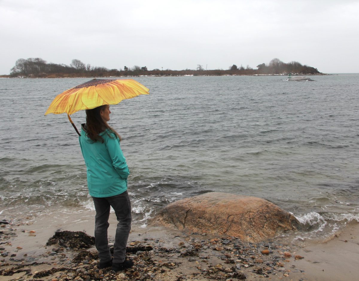 Woman holding umbrella on a Long Island Sound beach on a rainy day