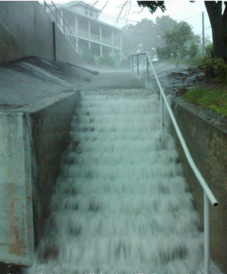 Stormwater pours down a public stairway in Groton City in a 2023 flood.