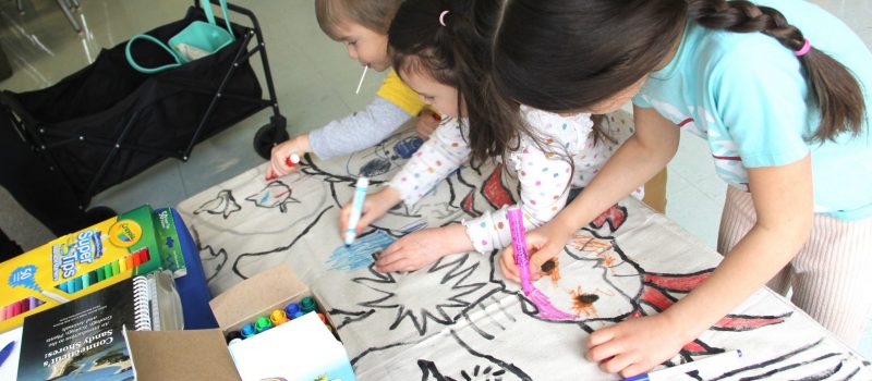 Three children coloring sea creature mural