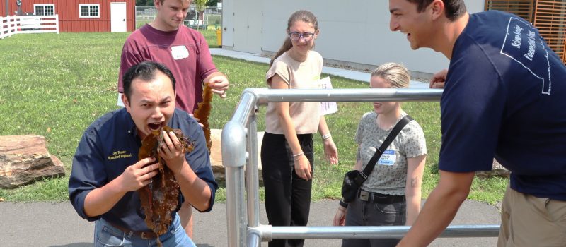 Connecticut Association of Agriculture Educators member Jon Russo gets a laugh from Clayton McGoldrick of CTSG as he pretends to bite into a mouthful of kelp after a lesson for educators in the mobile aquaculture lab at Vernon High School on Aug. 11.