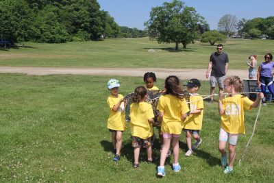 A group of kindergarteners carry a lobster trap during Marine Science Day at Waterford Town Beach.