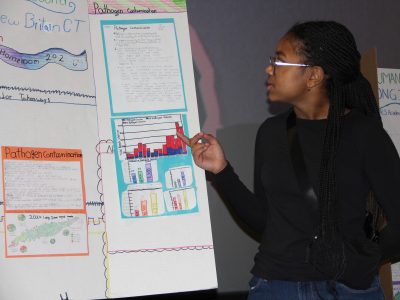 Peyton Harper, a 7th grader at HALS Academy in New Britain, talks about pathogen contamination at beaches during a poster presentation at the symposium.